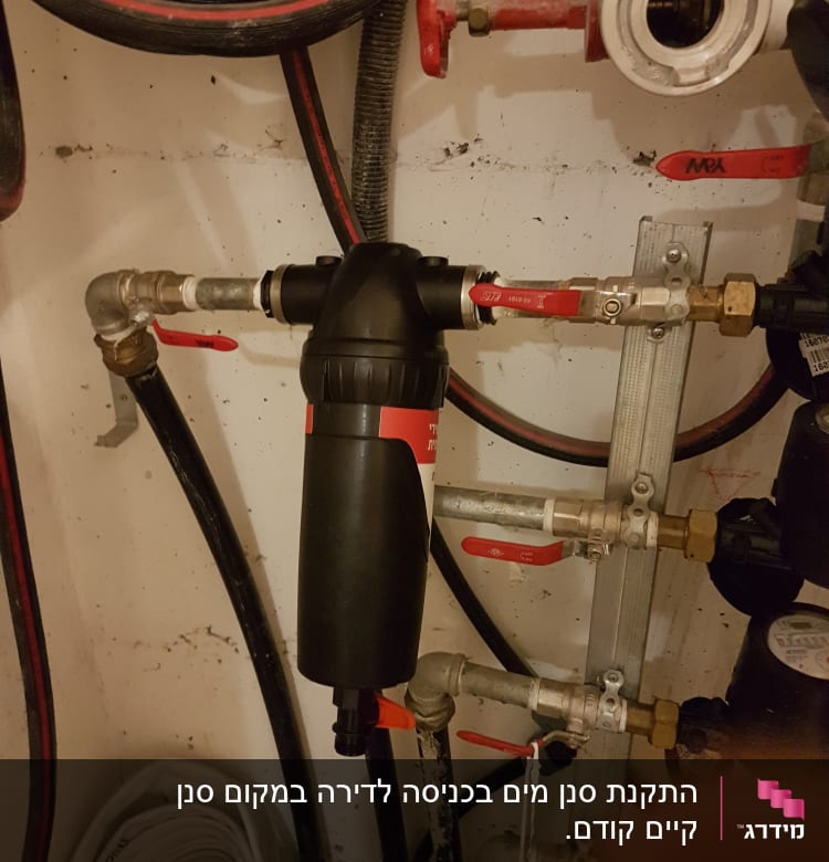 צנרת עם ברזים אדומים ומסנן מים שחור